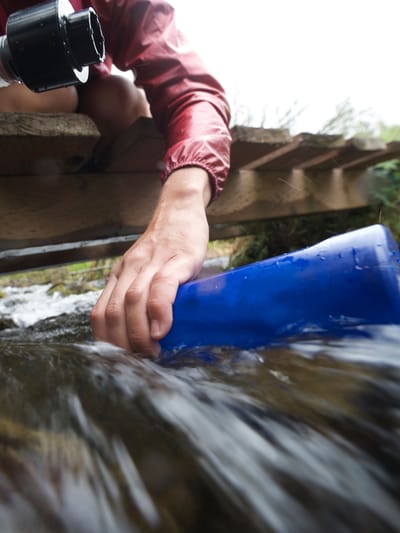 a female hiker filling up her water bottle to showcase portable water filter rv options